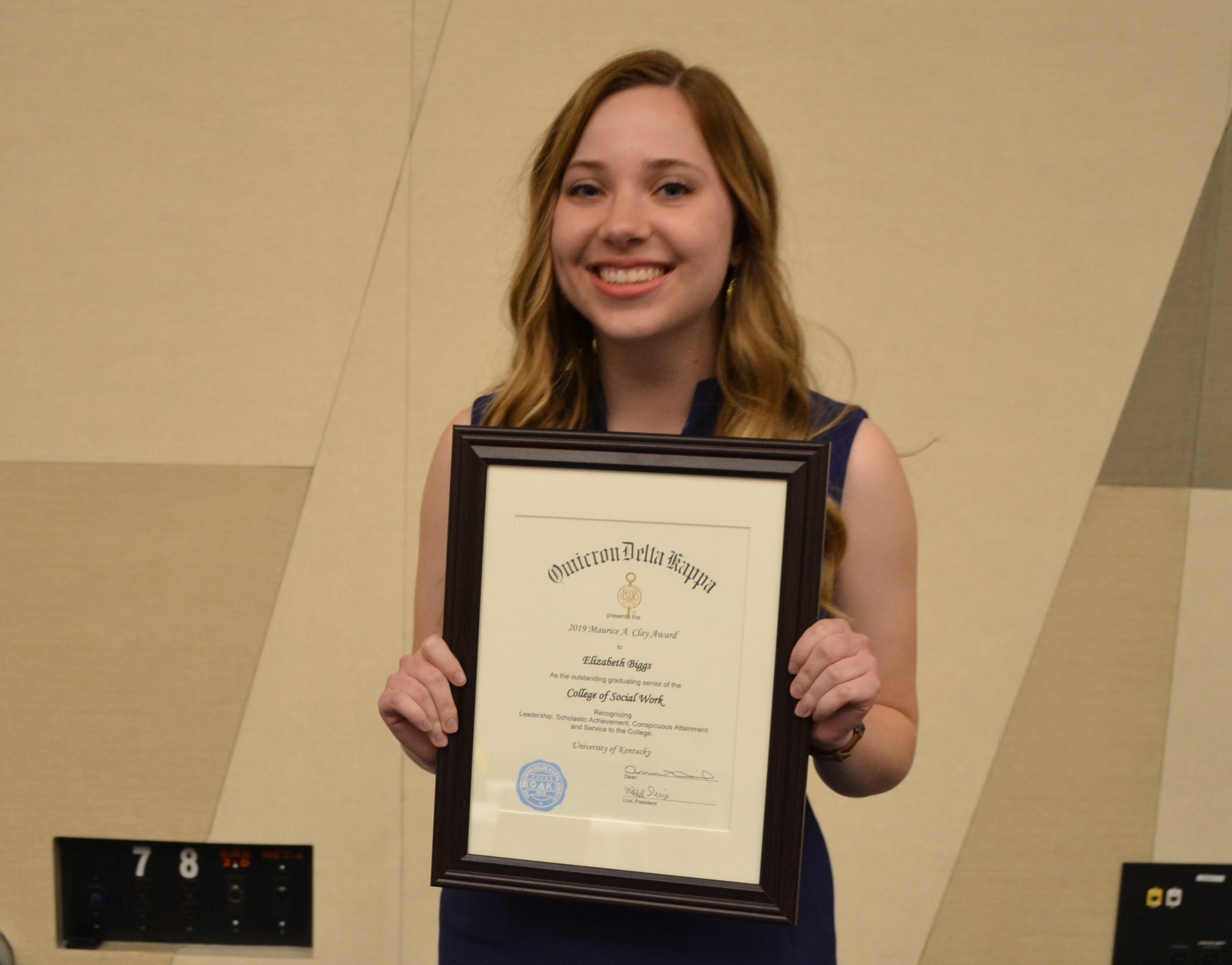 Elizabeth Biggs, with light brown hair and a dress, holding the Claw Award