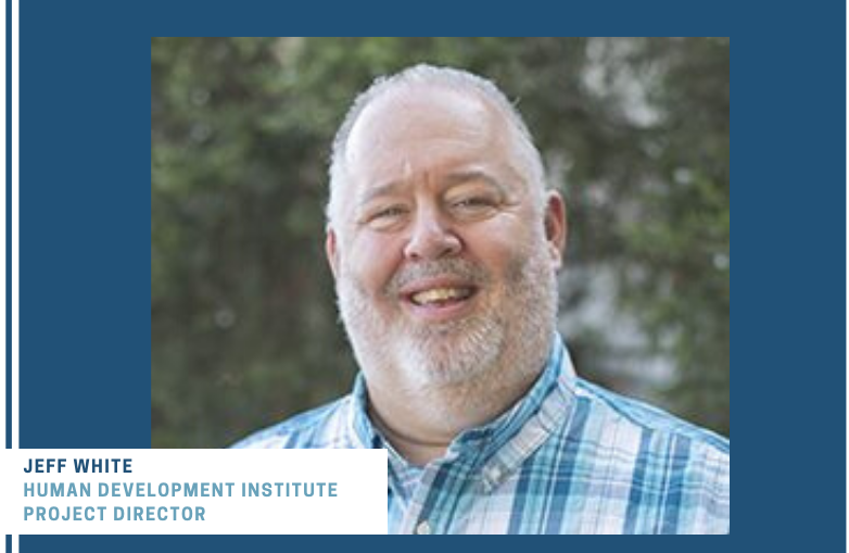 Man with gray beard smiling wearing blue shirt