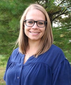 Chelsea Naugle staff photo. She is wearing glasses and a blue blouse and has shoulder-length, straight brown hair.