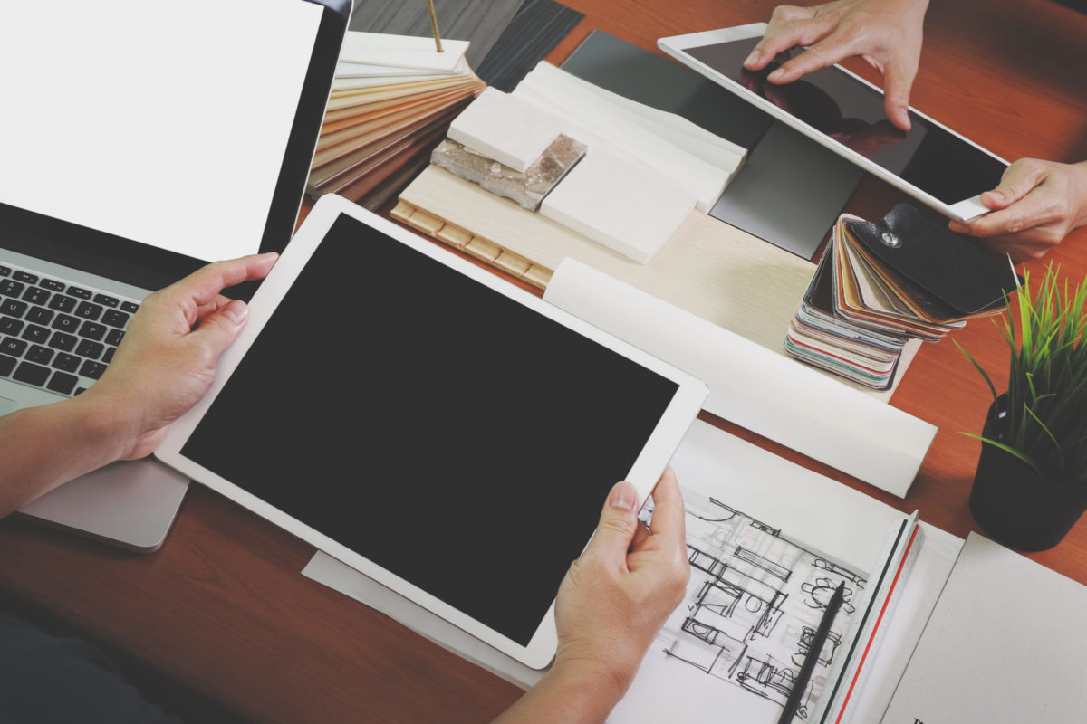 tablet next to a laptop over a desk covered with papers