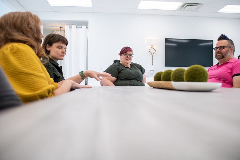 4 people seated at a conference room table having a discussion