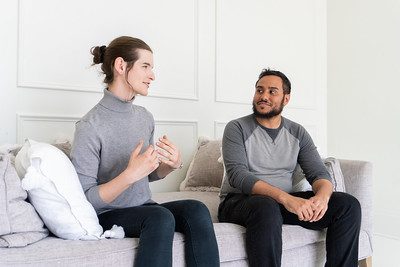 two people seated on a couch talking