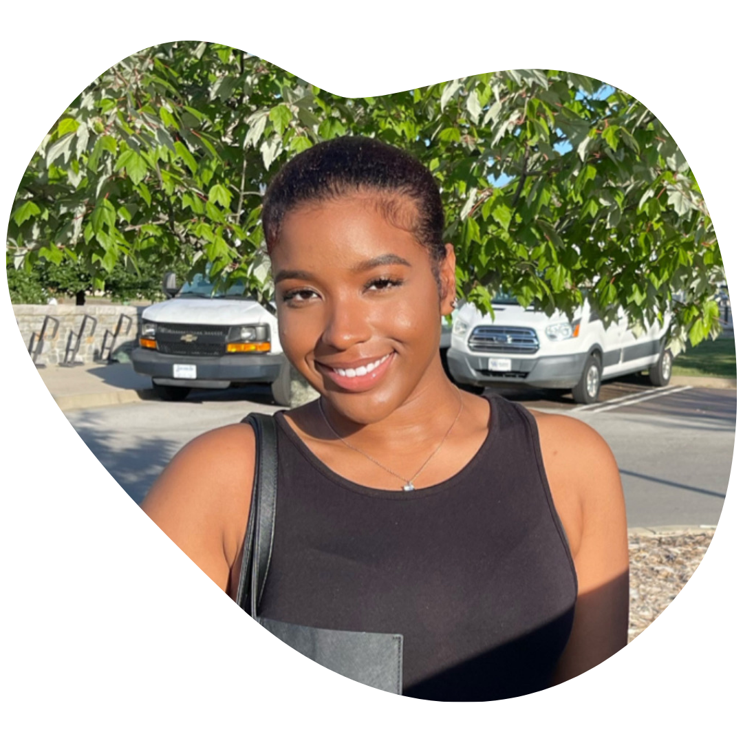 jade forest staff photo, she is wearing a black tank top, smiling for the camera in front of trees